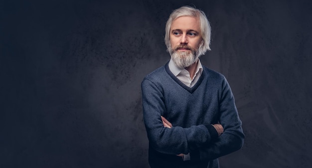 Portrait d'un beau mâle mature avec une barbe grise isolé sur un fond sombre.