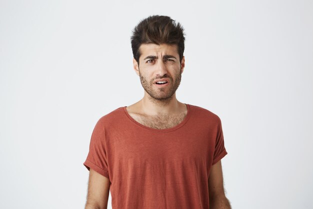 Portrait d'un beau mec bronzé avec une coiffure élégante et une barbe folle de mots grossiers dans sa direction de son ex-petite amie.