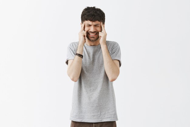 Portrait de beau mec posant contre le mur blanc