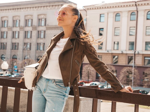 Portrait de beau modèle brune souriante vêtue de vêtements de veste hipster d'été