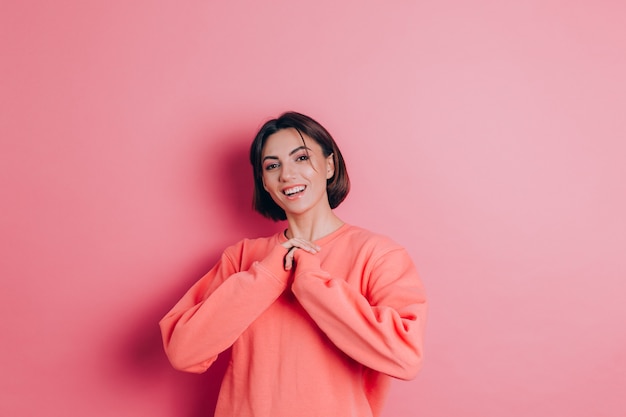 Portrait de beau modèle de femme brune mignonne souriante dans des vêtements de pull pêche décontracté avec maquillage lumineux et lèvres roses isolées