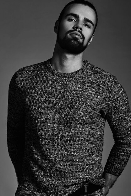 portrait de beau modèle hipster élégant de mode vêtu d'un pull chaud qui pose en studio.