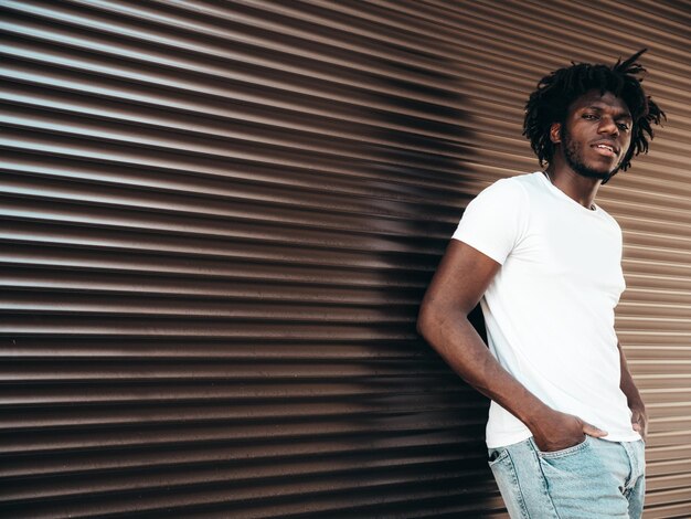 Portrait d'un beau modèle hipster Homme africain mal rasé vêtu d'un t-shirt d'été blanc et d'un jean