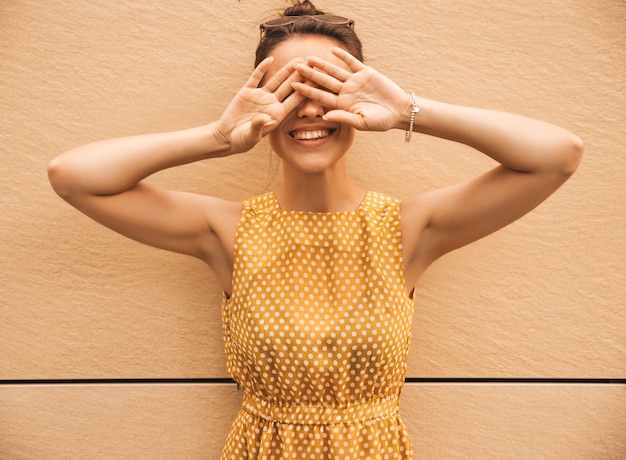 Portrait de beau modèle hipster souriant vêtu d'une robe d'été jaune. Fille branchée posant dans la rue. Femme drôle et positive s'amuser