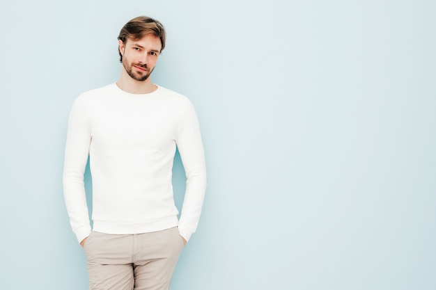 Photo gratuite portrait d'un beau modèle d'homme d'affaires lumbersexual hipster souriant portant un pull et un pantalon blancs décontractés