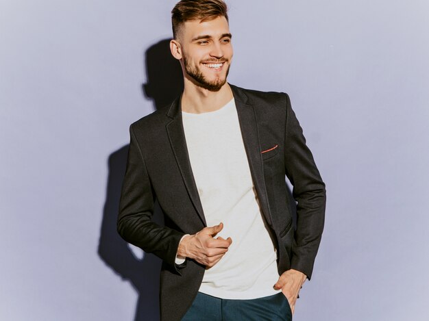 Portrait de beau modèle d'homme d'affaires souriant hipster portant un costume noir décontracté.