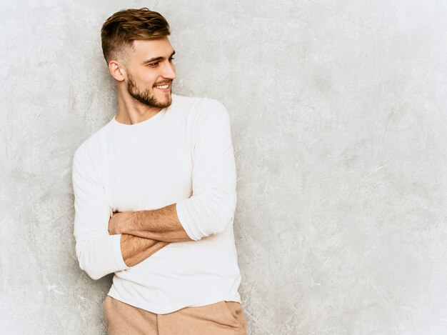 Portrait de beau modèle d'homme d'affaires souriant hipster portant des vêtements décontractés d'été blanc .. Bras croisés