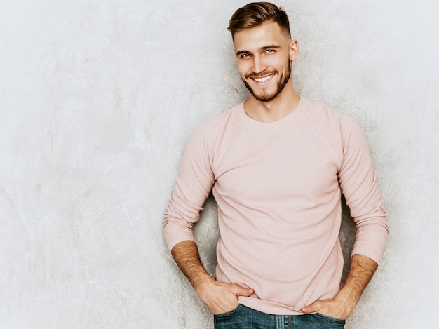 Portrait de beau modèle jeune homme souriant portant des vêtements décontractés d'été rose. Homme élégant de mode posant