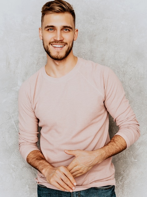 Portrait de beau modèle jeune homme souriant portant des vêtements décontractés d'été rose. Homme élégant de mode posant