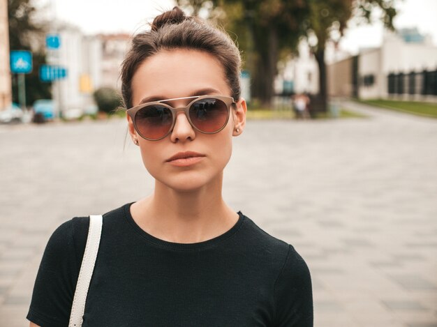 Portrait de beau modèle souriant vêtu de vêtements d'été. Fille branchée posant dans la rue en lunettes de soleil. Femme drôle et positive s'amuser