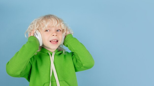 Portrait de beau petit garçon caucasien isolé sur le mur bleu du studio