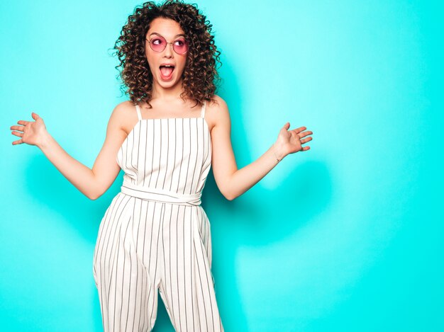 Portrait, de, beau, sourire, modèle, à, afro, boucles, coiffure, habillé, dans, été, hipster, girl., Sexy, insouciant, girl, poser, près, mur bleu., Tendance, drôle, et, positif, woman., Choqué, et, surpris