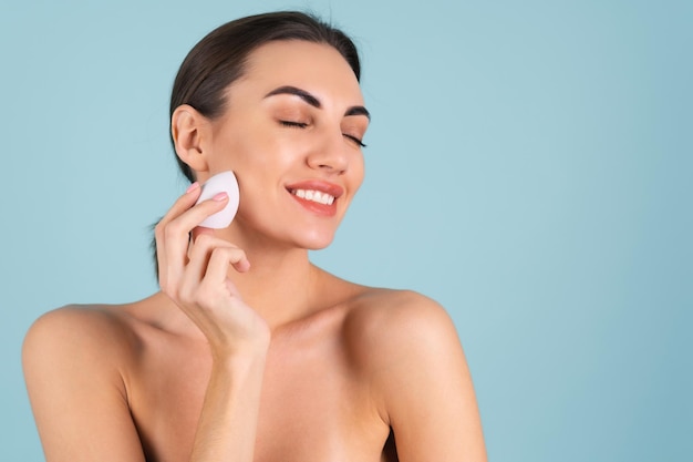 Portrait de beauté en gros plan d'une femme avec une peau parfaite et un maquillage naturel, des lèvres nues charnues, tenant une éponge de maquillage