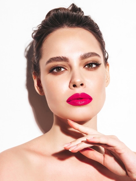 Photo gratuite portrait de beauté de mode de jeune femme brune avec un maquillage élégant de soirée et une peau propre parfaite modèle sexy avec des cheveux en chignon qui pose en studio avec des lèvres naturelles brillantes roses