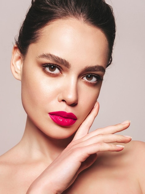 Portrait de beauté de mode de jeune femme brune avec un maquillage élégant de soirée et une peau propre parfaite Modèle sexy avec des cheveux en chignon qui pose en studio Avec des lèvres naturelles brillantes roses