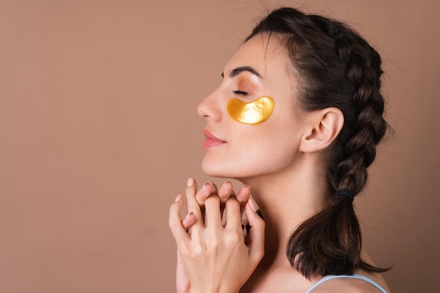 Portrait de beauté proche d'une femme avec une peau parfaite et des taches dorées de maquillage naturel sous les yeux pour hydrater la peau et soulager les poches du visage