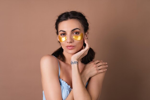 Portrait de beauté proche d'une femme avec une peau parfaite et des taches dorées de maquillage naturel sous les yeux pour hydrater la peau et soulager les poches du visage