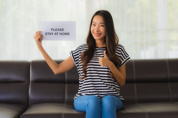 Portrait de beaux jeunes spectacles papier avec phrase rester à la maison sur le canapé