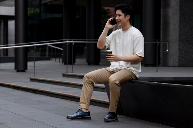 Portrait d'un bel homme asiatique utilisant un smartphone à l'extérieur de la ville