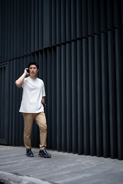 Portrait d'un bel homme asiatique utilisant un smartphone à l'extérieur de la ville