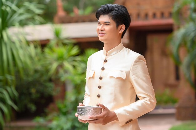 Portrait bel homme dans de beaux costumes thaïlandais debout avec un bol d'eau dans le temple sur Songkran festival Thai New Year Family Day en avril