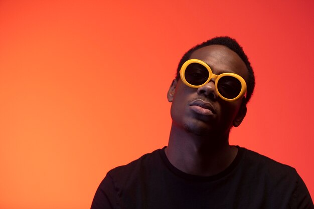 Portrait de bel homme avec des lunettes de soleil sur fond orange