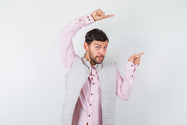 Portrait d'un bel homme pointant vers le côté droit en gilet, chemise et à la surprise