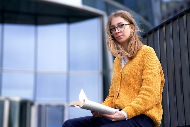 Portrait d'une belle adolescente lectrice dans des lunettes, étudiante à l'université ou à l'université, jeune jolie