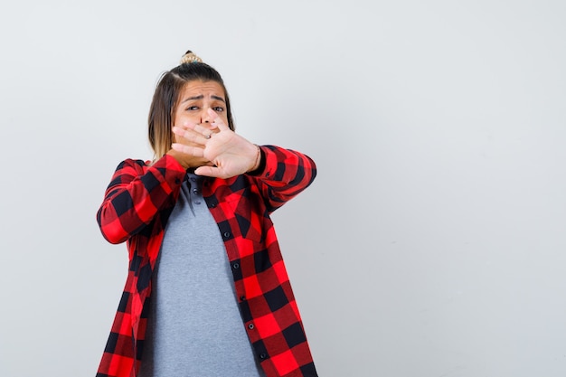 Portrait d'une belle dame montrant un geste d'arrêt, tenant la main sur la bouche dans des vêtements décontractés et regardant la vue de face effrayée