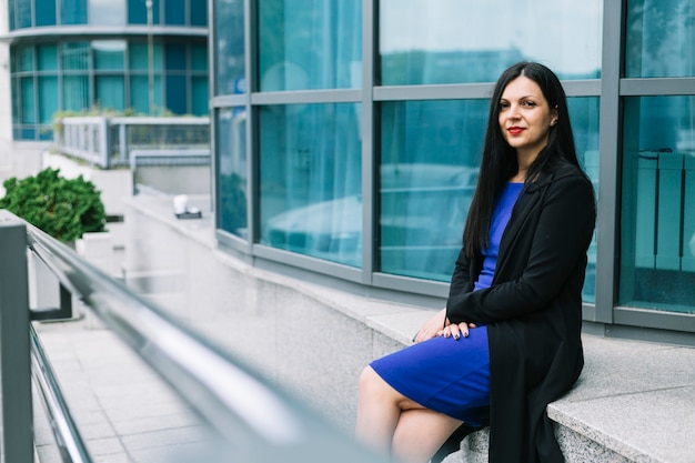 Portrait d'une belle femme d'affaires assis à l'extérieur de l'immeuble de bureaux