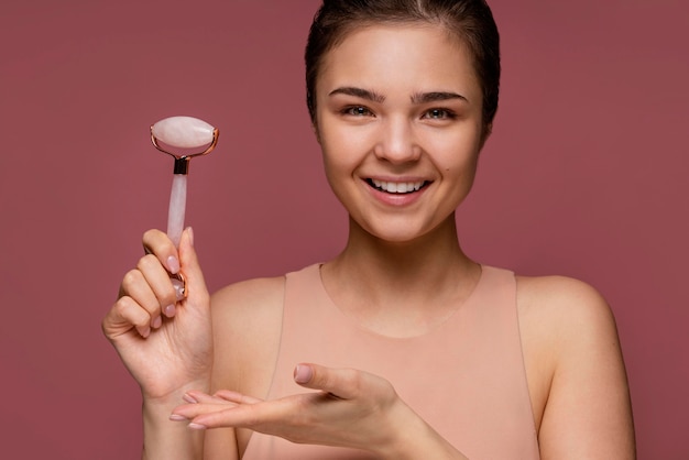 Photo gratuite portrait de belle femme à l'aide d'un rouleau de jade