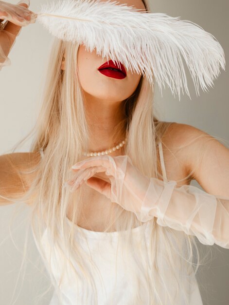 Portrait de belle femme albinos avec plume blanche