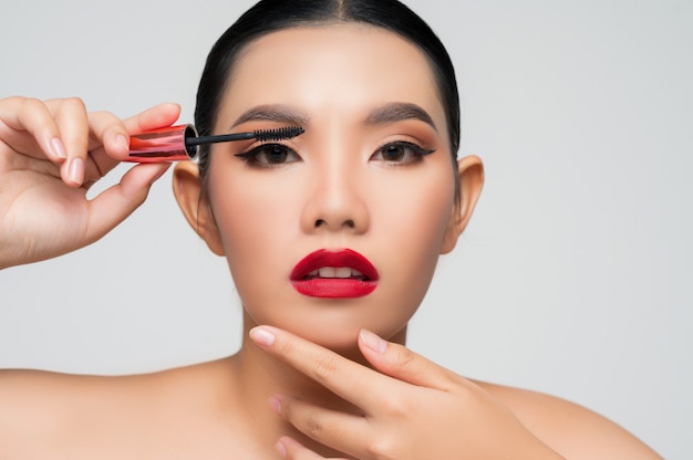 Portrait de belle femme asiatique avec du mascara à la main