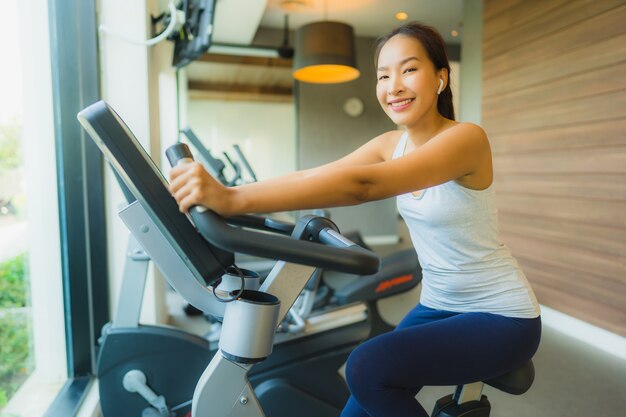 Portrait belle femme asiatique jeune sport exercer et travailler avec des appareils de fitness dans la salle de gym
