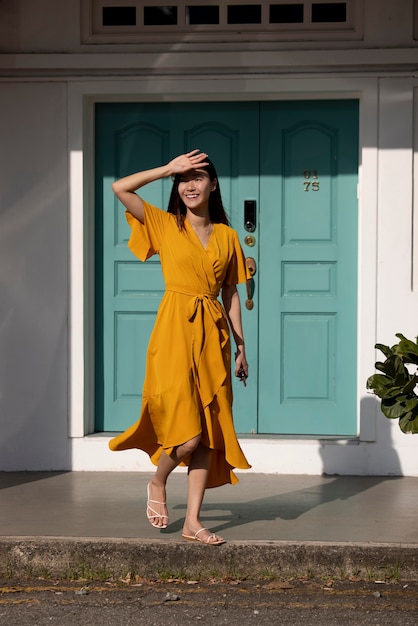 Portrait de belle femme asiatique en robe jaune posant à l'extérieur de la ville