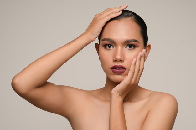 Le portrait de la belle femme asiatique touche la joue et le front