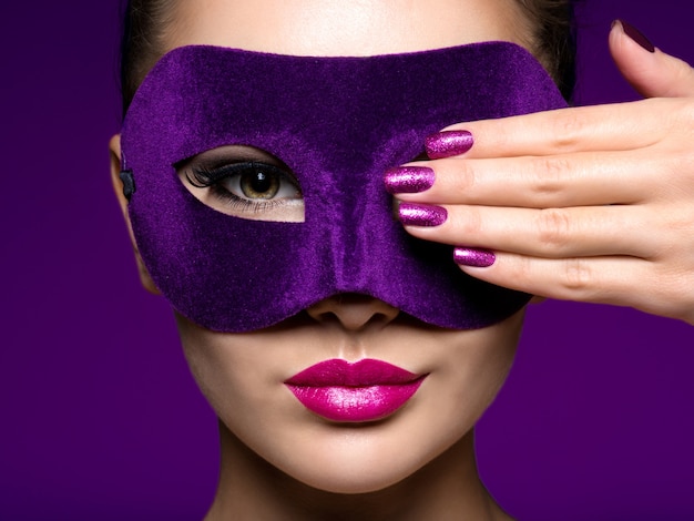 Photo gratuite portrait d'une belle femme aux ongles violets et masque de théâtre violet sur le visage.