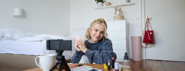 Portrait d'une belle femme blonde. Une fille montre des produits de beauté qui rougissent et enregistre une vidéo sur numérique.