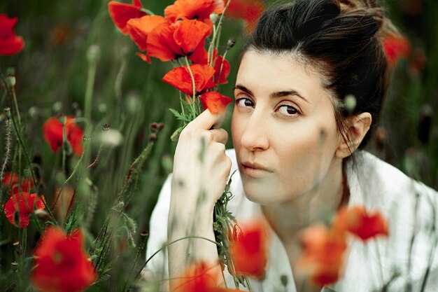 Portrait de la belle femme avec le bouquet de fleurs de coquelicots