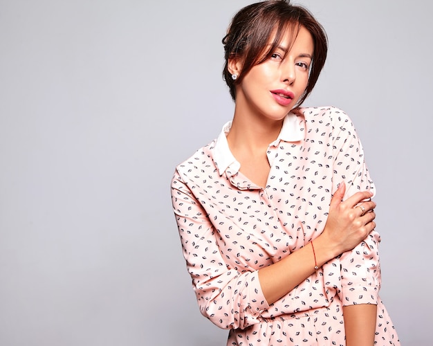 Portrait de la belle femme brune mignonne modèle dans des vêtements d'été décontractés sans maquillage isolé sur mur gris