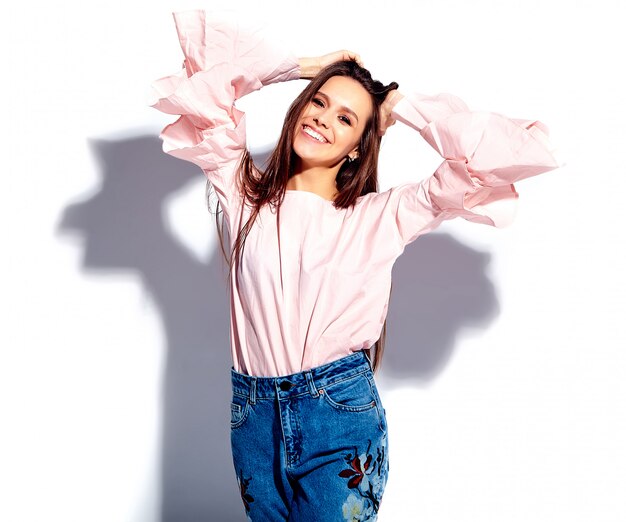 Portrait de la belle femme brune souriante caucasien modèle en chemisier rose vif et élégant jean bleu avec imprimé fleurs