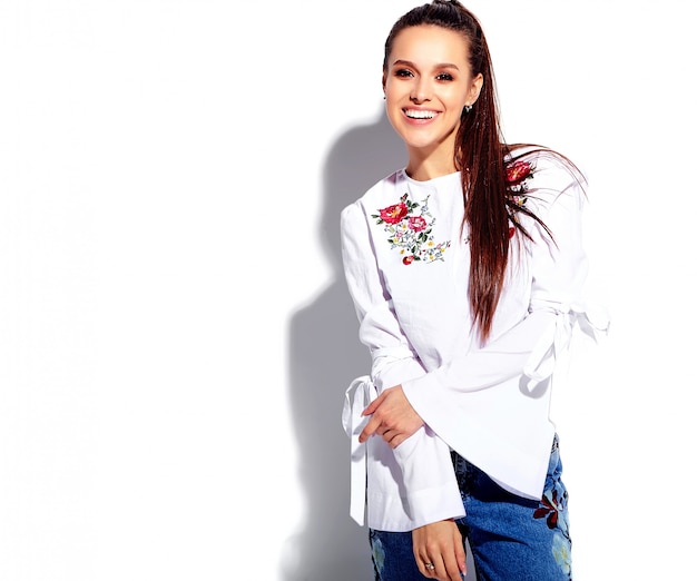 Portrait de la belle femme brune souriante caucasienne modèle en blouse blanche et jeans bleu élégant d'été