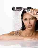 Photo gratuite portrait d'une belle femme brune tient la douche dans les mains avec de l'eau qui tombe