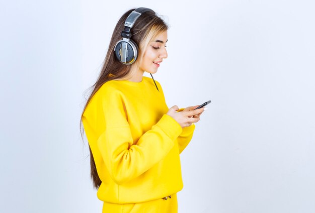 Portrait d'une belle femme avec un casque à l'aide d'un téléphone portable