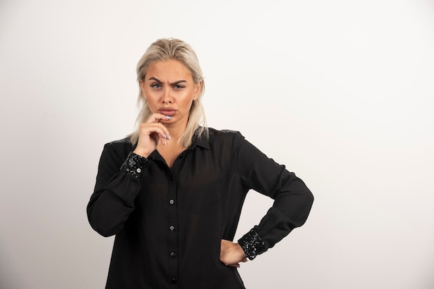 Portrait de la belle femme en chemise noire posant sur fond blanc. Photo de haute qualité