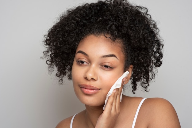 Portrait d'une belle femme enlevant son maquillage avec un tissu