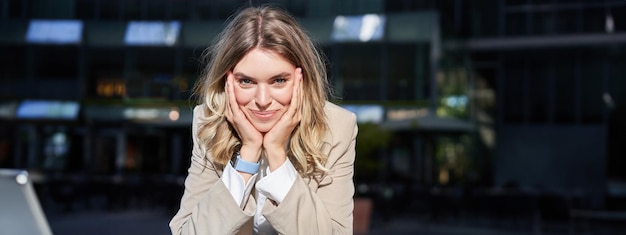 Photo gratuite portrait d'une belle femme d'entreprise heureuse en costume se tient dans la rue et sourit pose près du bureau