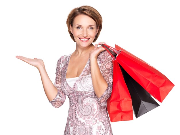 Portrait d'une belle femme heureuse avec un geste de présentation et des sacs à provisions sur un espace blanc