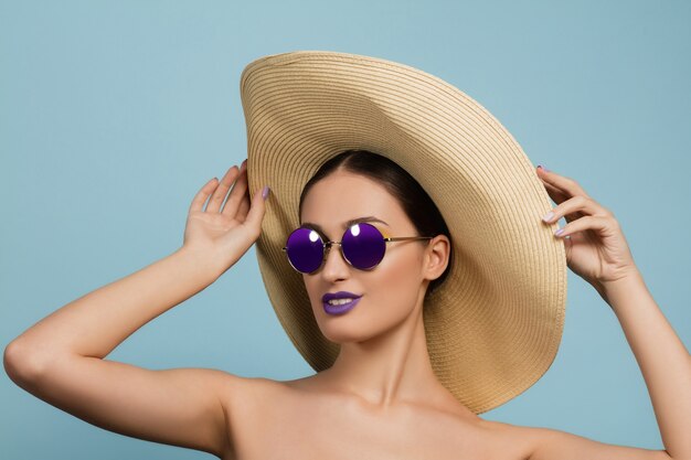 Portrait de belle femme avec maquillage lumineux, chapeau et lunettes de soleil. Marque et coiffure élégantes et à la mode.