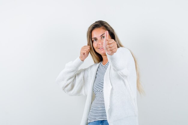 Portrait de belle femme montrant le pouce vers le haut dans la veste et à la vue de face joyeuse